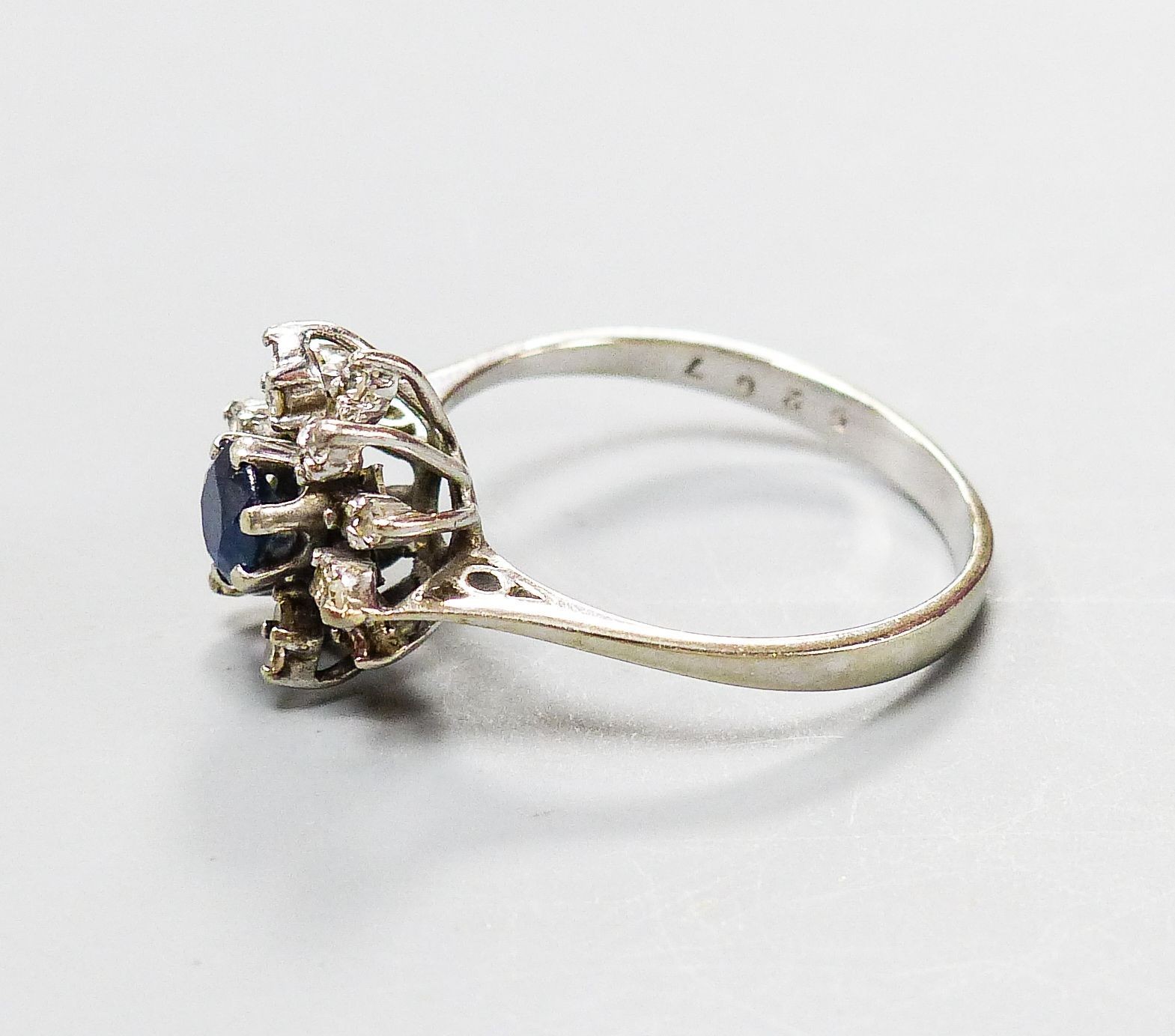 An 18ct white metal, sapphire and diamond set flower head cluster ring, size O, gross 3 grams.